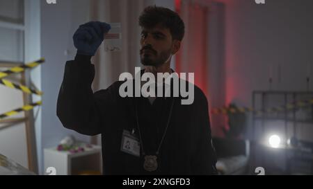 Hispanic detective man examines evidence at indoor crime scene with serious expression Stock Photo