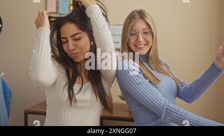Two women dancing joyfully together in a cozy living room setting, showcasing friendship and leisure at home. Stock Photo