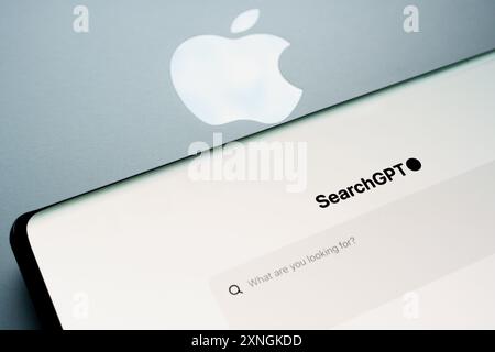 OpenAI SearchGPT page seen on the smartphone screen placed next to macbook wth Apple logo. Concept. Stafford, United Kingdom, July 31, 2024 Stock Photo