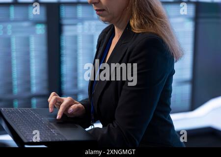 Software developer in data center checking rigs and hardware, doing checkup. Close up of employee planning and executing high tech server hub facility migrations and upgrades using device Stock Photo