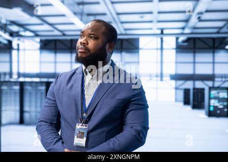 Engineer walking in data center, configuring and managing network infrastructure, such as routers, switches and firewalls. IT expert in server hub looking for technical issues Stock Photo