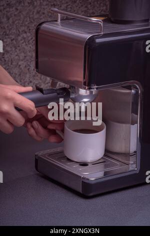 Woman Barista operates a machine to prepare delicious coffee, Close-up of hands using the coffee machine preparing an espresso coffee. Stock Photo