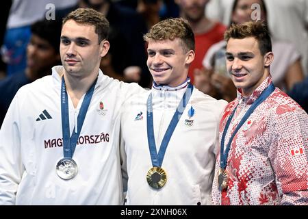 Paris, France. 31st July, 2024. Kristof Milak of Hungary, silver, Leon Marchand of France, gold, and Ilya Kharun of Canada, bronze attend the medal ceremony of the swimming 200m Butterfly Men Final during the Paris 2024 Olympic Games at La Defense Arena in Paris (France), July 31, 2024. Credit: Insidefoto di andrea staccioli/Alamy Live News Stock Photo