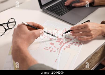 Cartographers working with cadastral map at white table in office, closeup Stock Photo