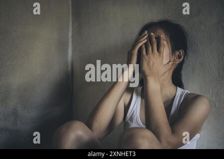 Young woman suffering from depression and anxiety sitting on the floor. The woman feels frustrated and confused, unhappy, personal problems, stress. Stock Photo