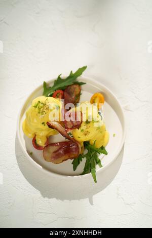 Savory breakfast delight: Eggs Benedict with bacon and fresh herbs Stock Photo