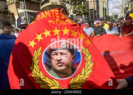 A supporter of the Venezuelan government wraps himself with a flag with the figure of Hugo Chavez, former president of Venezuela and historical leader of the Bolivarian revolution. Hundreds of people marched down Urdaneta Avenue in support of President Nicolas Maduro. During their march to the Miraflores presidential palace, the marchers carried flags and symbols of support in allusion to Chavismo and the current president. This demonstration was organized after Maduro announced his security plan in which he foresees “civic, police and military patrols” throughout the national territory. (Phot Stock Photo