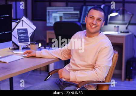 Handsome programmer working with computer in office at night Stock Photo