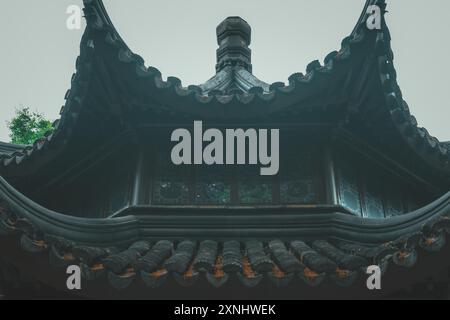 A low angle view of a traditional Chinese temple roof with intricate details and a window. Stock Photo