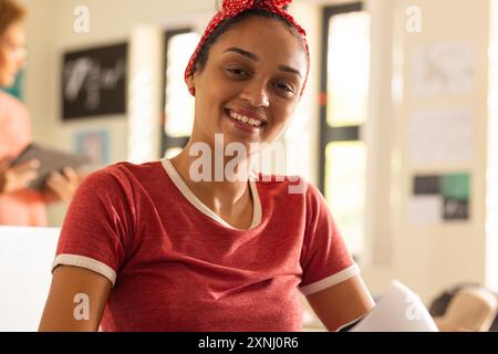 Smiling teenager in high school holding papers in classroom, feeling happy Stock Photo