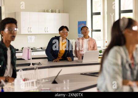 Wearing safety goggles, teenagers in high school science classroom engaging in experiment Stock Photo