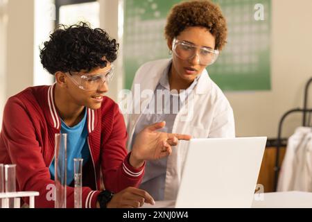 In high school, teenagers using laptop and discussing science project in laboratory Stock Photo