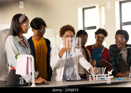 Wearing safety goggles, students in high school observing teacher conducting science experiment Stock Photo