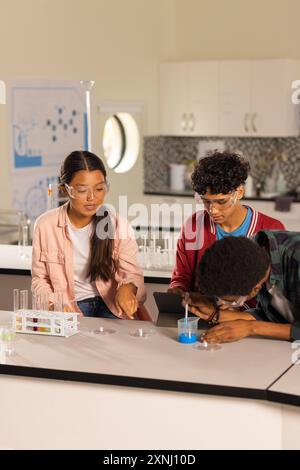 Conducting science experiment with test tubes and tablet, students in high school laboratory Stock Photo