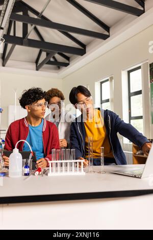 In high school laboratory, teenagers conducting science experiment with ...