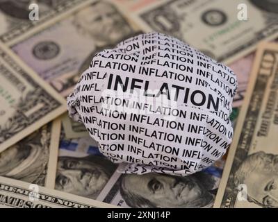 Crumpled paper ball with words Inflation lying on a United States Dollar bills background. Stock Photo