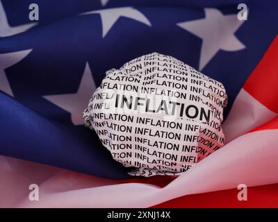 Crumpled paper ball with words Inflation lying on an American flag. Stock Photo