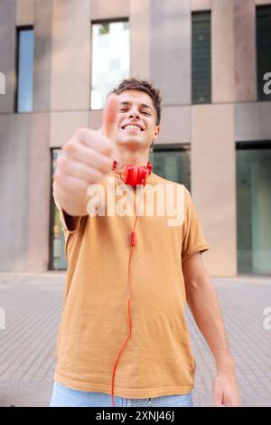 portrait Young Caucasian man pointing thumb up looking smiling at camera. Stock Photo