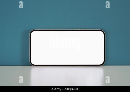 Modern smartphone with blank screen showcasing a white display against a blue background, perfect for mobile app presentations Stock Photo
