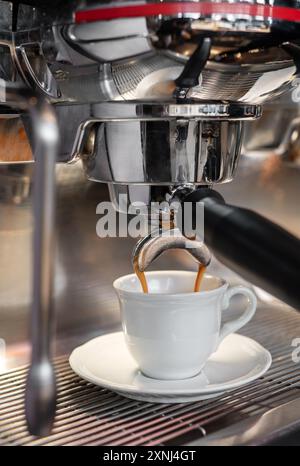 Professional espresso machine pouring coffee in a white cup standing on a saucer Stock Photo