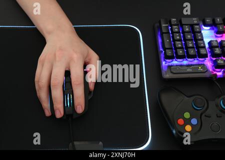 Gamer using modern wired computer mouse at dark table, above view Stock Photo