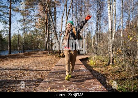 Happy woman enjoying pastime hiking in forest raising hands up, breathing in fragrance of autumn air Stock Photo