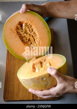 Two halves of melon are held in hands Stock Photo