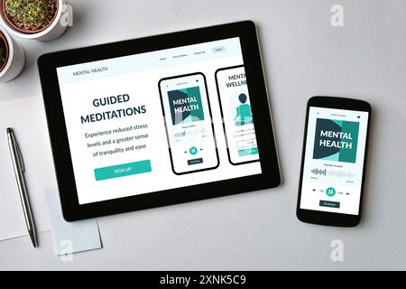 Meditation app on tablet and smartphone screen over gray table. Mental health app concept. Top view Stock Photo