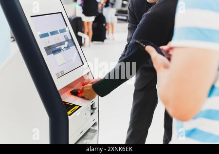 Male passenger doing self check in for flight at modern airport. Stock Photo