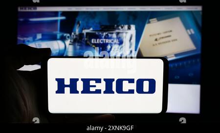 Person holding cellphone with logo of US aerospace company HEICO Corporation in front of business webpage. Focus on phone display. Stock Photo