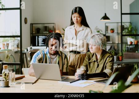 Diverse group of gen Z man and women wearing casual clothes working together on business project in modern eco-friendly office Stock Photo