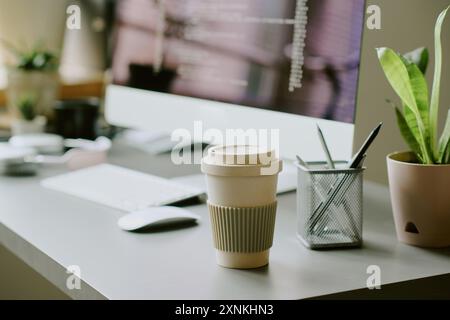 No people shot of reusable coffee cup on table at workplace in modern IT company office Stock Photo