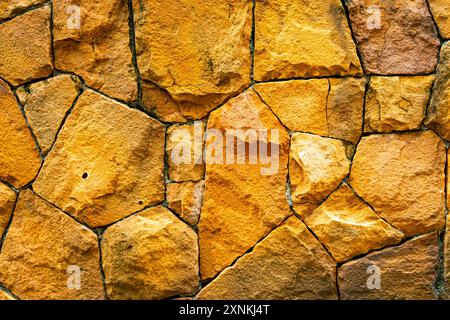 Closeup of rough texture surface of old orange limestone wall. Abstract outdoor dirty stonewall background. Stock Photo