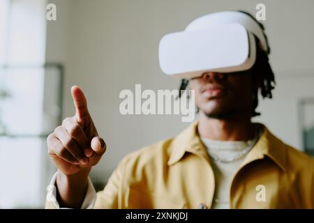 Medium closeup of young African American male developer wearing VR headset testing new software, copy space Stock Photo