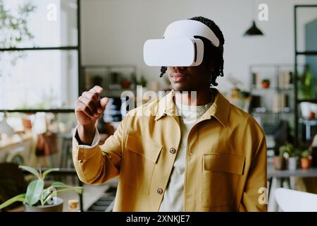 Medium shot of gen Z African American male developer wearing VR headset testing new app at work in leading IT company office Stock Photo