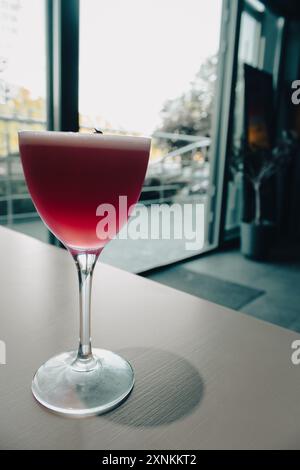 Cosmopolitan cocktail on the table. Elegant glass of red cocktail in empty cafe. Cold drinks concept. Summer cafe interior. Icy alcohol cocktail. Stock Photo