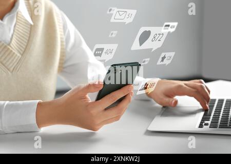 Content manager. Woman working on laptop and smartphone indoors, closeup. Likes, followers, e-mails, messages and adding to favorite notifications ove Stock Photo