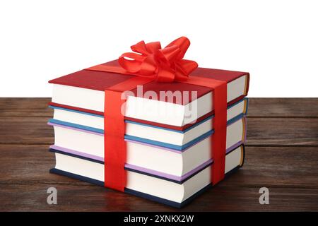 Stack of books with ribbon as gift on wooden table against white background Stock Photo