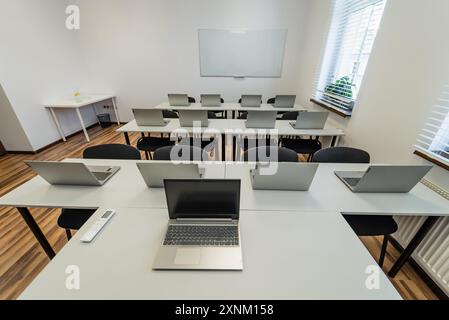 Interior of a modern classroom with desks, chairs and laptops. Empty conference room with laptop on table in office.  Office Business. Conference room Stock Photo