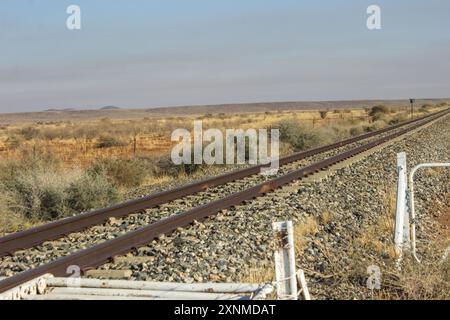 A railway track going through the flat and dry shrublands of the Nama Karoo in the Northern Cape of South Africa. Stock Photo