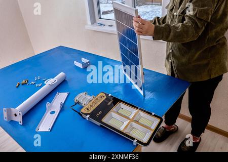 Bracket for mounting solar panel and LED light of street lighting, user prepares for installation. Stock Photo