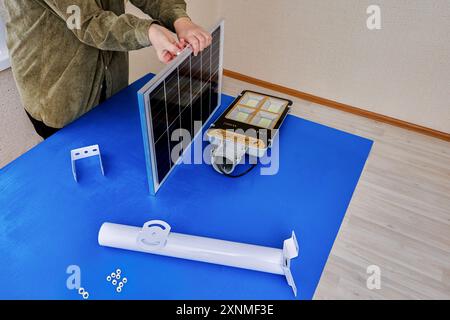 Solar panel and LED outdoors light will be fixed on mounting bracket before being installed on outside wall of house or street pole. Stock Photo