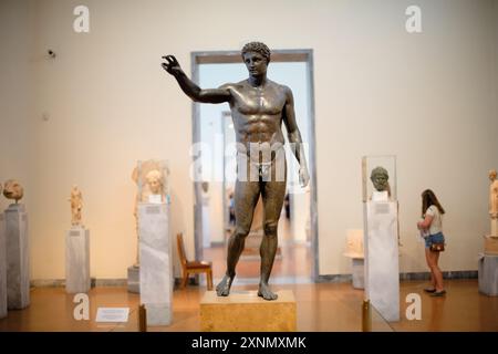 ATHENS, Greece — The Antikythera Ephebe, also known as the Antikythera Youth, is a prominent bronze sculpture displayed at the National Archaeological Museum in Athens. Recovered from the Antikythera shipwreck, this statue dates back to the late 4th century BC and represents an idealized young male figure, showcasing the artistic and cultural significance of the Hellenistic period. The Antikythera Ephebe is noted for its realistic portrayal and intricate craftsmanship, highlighting the excellence of ancient Greek sculptors. Stock Photo