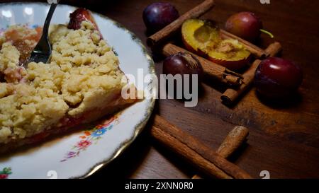 Homemade plum cake on a plate, a fork, plums, cinnamon. Stock Photo