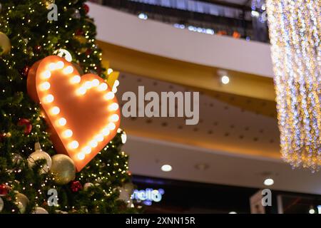 Blurred background, heart-shaped bokeh lights on the Christmas tree are beautifully decorated and the heart symbol signifies love, friendship and kind Stock Photo