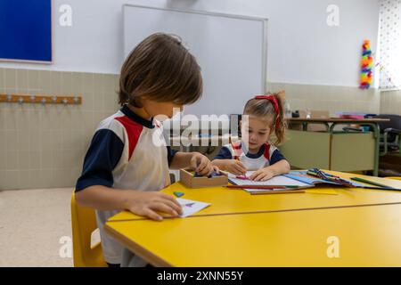 Children in kindergarten doing puzzles at the desk. Stock Photo