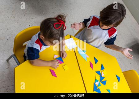 Children in kindergarten doing puzzles at the desk. Stock Photo