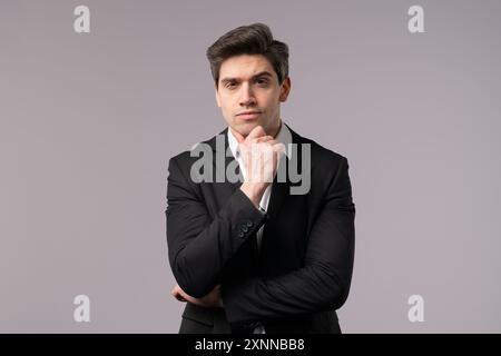 Thinking man looking up and around on grey background. Worried contemplative face expressions. Handsome male model in formal suit Stock Photo