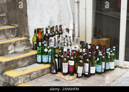 A selection of empty bear and wine bottles outside a bar on some steps. Hong Kong - 27th May 2024 Stock Photo