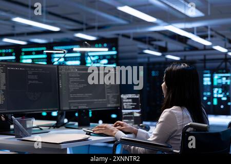 Person with paraplegia working in inclusive server farm facility, doing maintenance job. Engineer in wheelchair doing tasks in high tech data center housing advanced gear Stock Photo